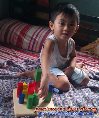 Filipino boy playing wooden toy blocks